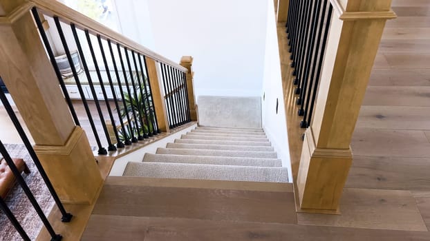 The image captures the detail of a well-designed modern staircase, lined with plush beige carpet, complemented by white walls and wooden balusters.