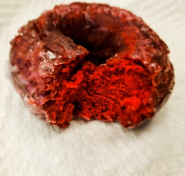 View of a Partially-eaten Red Velvet Donut Sitting on a Paper Napkin