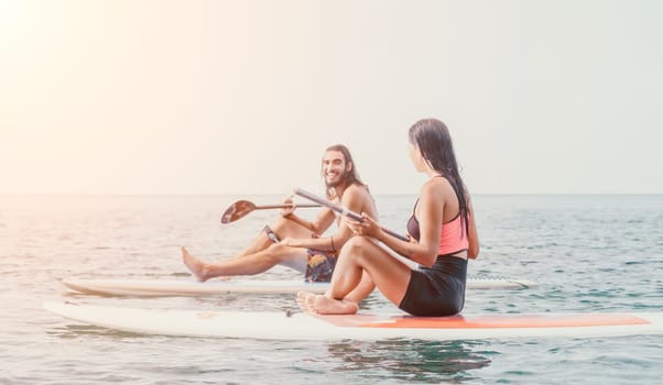 Woman man sup yoga. Happy young sporty couple practising yoga pilates on paddle sup surfboard. Female stretching doing workout on sea water. Modern family outdoor summer sport activity