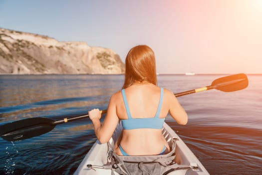 Woman in kayak back view. Happy young woman with long hair floating in transparent kayak on the crystal clear sea. Summer holiday vacation and cheerful female people relaxing having fun on the boat