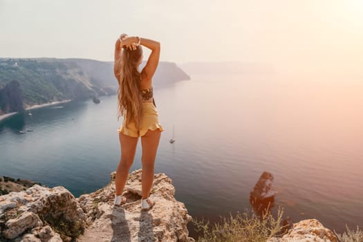 Woman travel sea. Happy tourist taking picture outdoors for memories. Woman traveler looks at the edge of the cliff on the sea bay of mountains, sharing travel adventure journey.