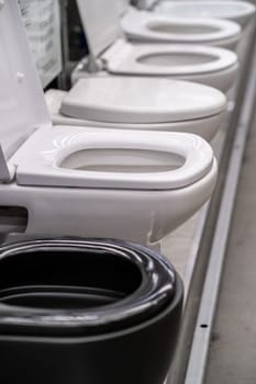 A row of grey automotive toilets are lined up in a store resembling automotive design elements such as bumpers, grilles, and hoods