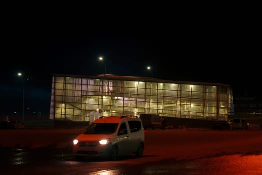 Windows glowing Illuminated Multi-Windowed Building at Night. Crossing the automobile highway