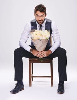 Studio, portrait and man with chair, bouquet and date for style and fashion. Gentleman, designer and romance with flowers, confidence and proud ambition with suit isolated on white background.
