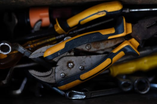 Box of Miscellaneous tools including screwdriver, pliers, spirit level in a jumble. All piled on top of each other. Close up of tools box.