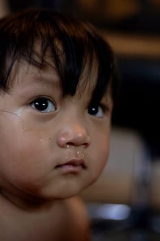 Crying boy with tear on cheek. Kid crying, focus on his tear.