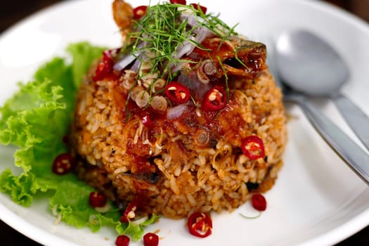 Thai food, Fried jasmine rice with canned fish mackerel in tomato sauce, topped with red chili, red onion, lettuce and kaffir lime leaves.