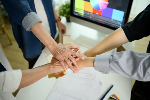 Above view of young businesspeople stacking hands over meeting table.