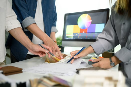 Group of creative people choosing paint color and discussing interior design project at office.