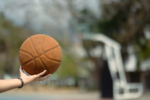 Hand holding a ball on an outdoor court. People, sport and active lifestyle concept.