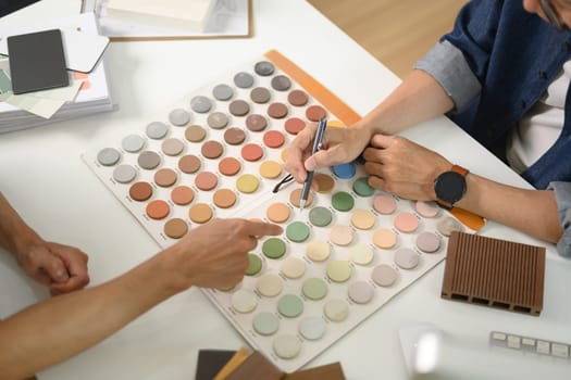 Interior designer or decorator helping customer choosing color palette for indoor decor.