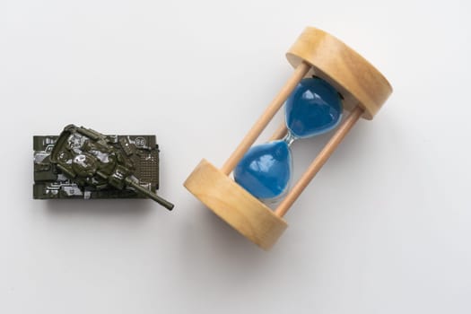 The plastic tank toys on the floor next to an hourglass. High quality photo