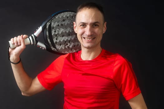 Smiling man with racket and paddle ball dressed in sport clothes isolated background. Front view. High quality photo