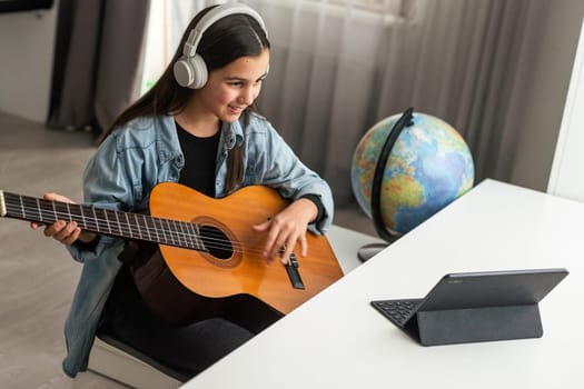 Beautiful young girl with long hair playing the guitar, sitting at home . studying the melody. Home leisure, hobbies, self-development. High quality photo