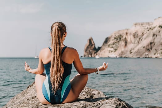 Yoga on the beach. A happy woman meditating in a yoga pose on the beach, surrounded by the ocean and rock mountains, promoting a healthy lifestyle outdoors in nature, and inspiring fitness concept