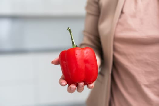 hand holding paprika or red sweet pepper isolated on white background. Fresh bell pepper or bulgarian pepper in male hairy hand as organic harvest concept. High quality photo