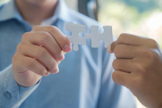 Two people holding a puzzle piece together. Concept of teamwork and collaboration. Scene is positive and uplifting, as it shows two people working together to solve a problem