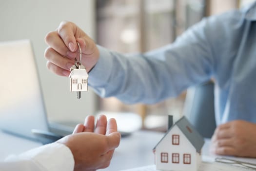 A real estate agent is handing home keys to a customer. After taking out a loan for buying and selling a house. Credit business, savings, real estate investment