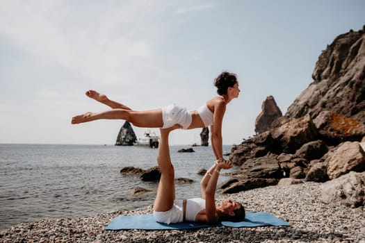 Woman sea yoga. Back view of free calm happy satisfied woman with long hair standing on top rock with yoga position against of sky by the sea. Healthy lifestyle outdoors in nature, fitness concept.