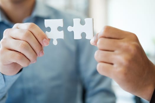 Two people holding a puzzle piece together. Concept of teamwork and collaboration. Scene is positive and uplifting, as it shows two people working together to solve a problem