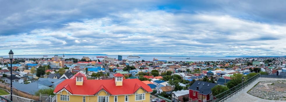 Vibrant coastal city with striking architecture and calm waters, captured in a panoramic view. Punta Arenas