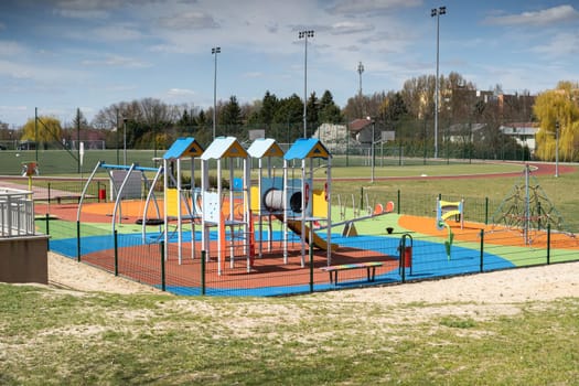 A separate and fenced play area for children with a safe, colorful surface. Children's outdoor playground.