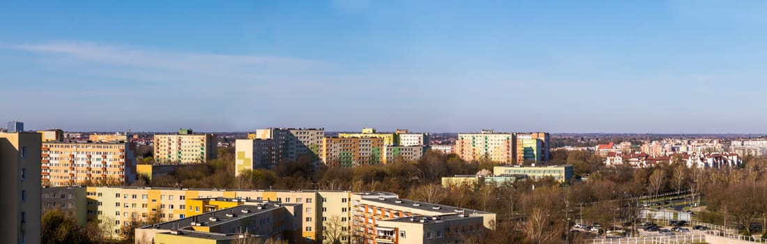 The whole city is bathed in the morning sun as part of Lublin's panorama. Lots of skyscrapers and lower buildings sufficient among the trees in early spring.