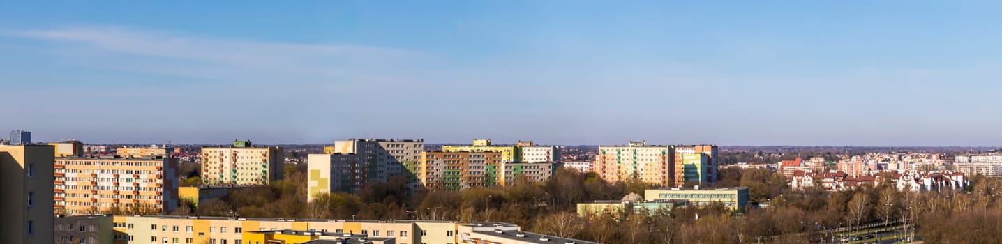 The whole city is bathed in the morning sun as part of Lublin's panorama. Lots of skyscrapers and lower buildings sufficient among the trees in early spring.