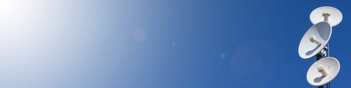 White telecommunications antennas on a single mast high above the city against the background of a blue sky. Technology of digital sending and receiving of data packets. Panoramic view. Blue background.