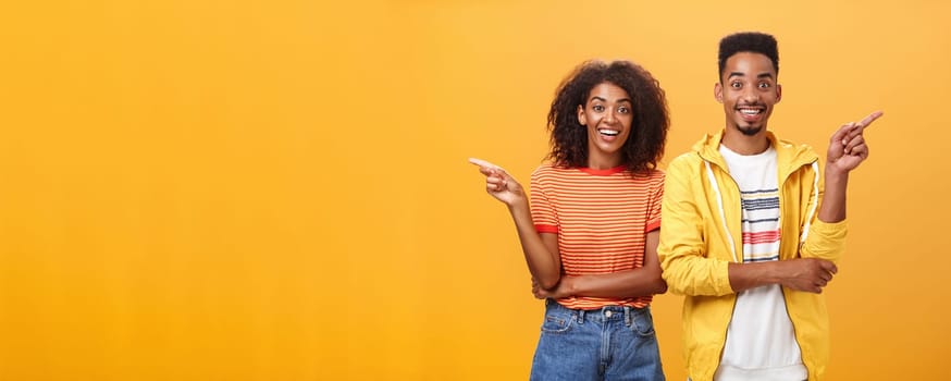 Which one telling true. Joyful and friendly good-looking couple, african american woman pointing left and dark-skinned guy right smiling broadly at camera giving advices but disagree with each other.