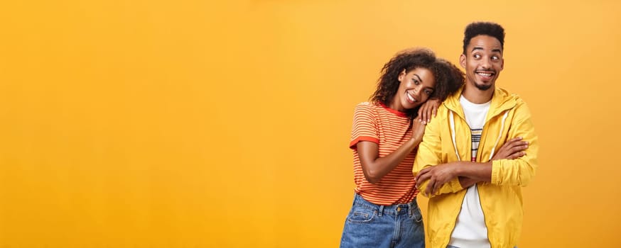 Guy feeling happy girl lean on his shoulder grinning and chuckling from happiness standing pleased and joyful over orange background while woman hugging best friend upbeat she can rely on him. Relationship concept