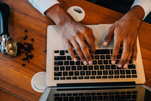 In the modern roastery office a multitasking business owner also a barista checks bean quality on laptop and machinery. Quality check assures premium coffee beans. Precision is the norm.