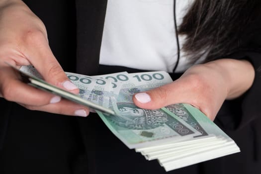 A close up shot when a businesswomen counts a thick stack of banknotes in Polish denomination.