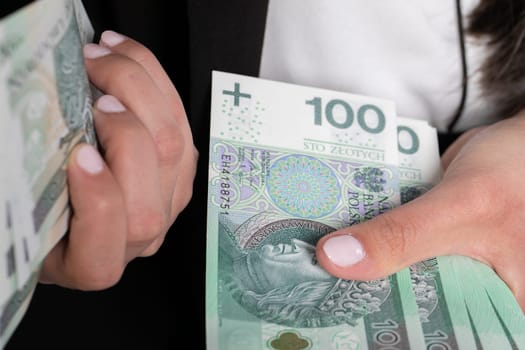 A close up shot when a businesswomen counts a thick stack of banknotes in Polish denomination.