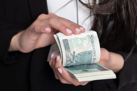 A close up shot when a businesswomen counts a thick stack of banknotes in Polish denomination.