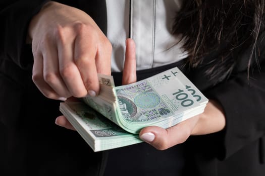 A close up shot when a businesswomen counts a thick stack of banknotes in Polish denomination.