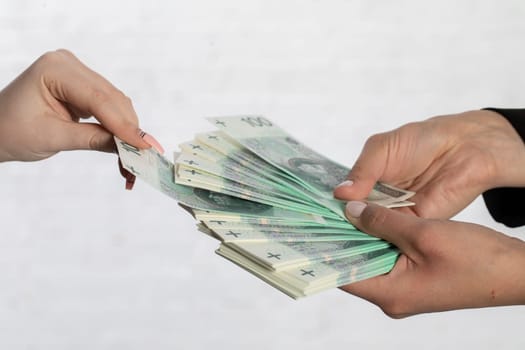 Spread-out fan-shaped paper banknotes hold young woman's hands.
