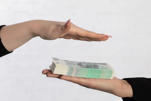One hand is held over a bundle of paper banknotes making a kind of roof over them.