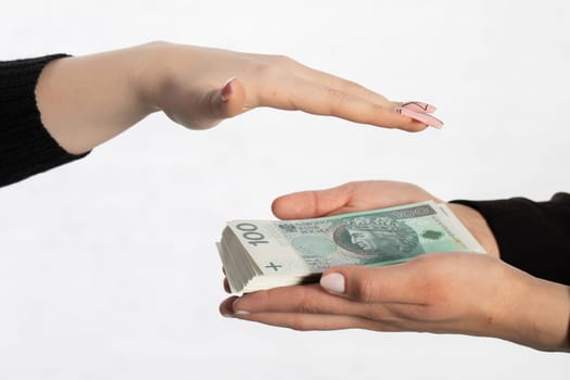 One hand is held over a bundle of paper banknotes making a kind of roof over them.