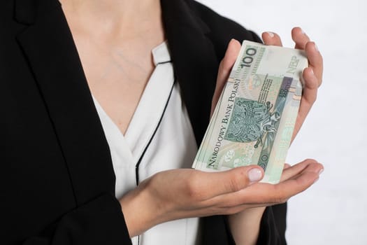A young teenager holds in her hands money with a face value of one hundred Polish zlotys.
