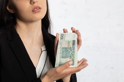 A young teenager holds in her hands money with a face value of one hundred Polish zlotys.