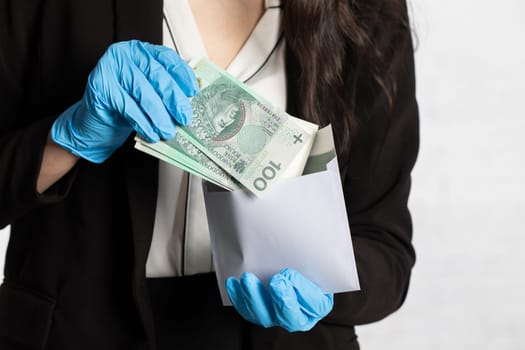 The woman slips a bundle of one hundred Polish zloty banknotes into a white envelope.