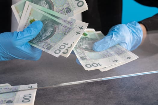 During an ongoing epidemic of infectious disease, the cashier gives cash in protective gloves.