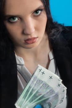 Hand counting banknotes by a young woman at the cashier's window in a large banking branch.