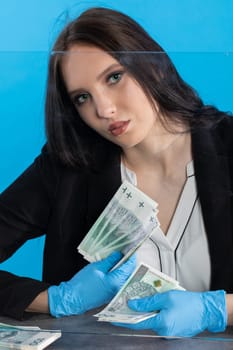 Hand counting banknotes by a young woman at the cashier's window in a large banking branch.