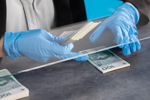 During an ongoing epidemic of infectious disease, the cashier gives cash in protective gloves.