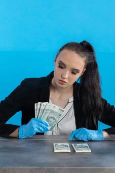 Hand counting banknotes by a young woman at the cashier's window in a large banking branch.