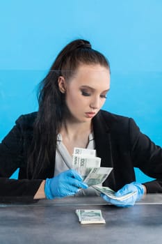 Hand counting banknotes by a young woman at the cashier's window in a large banking branch.