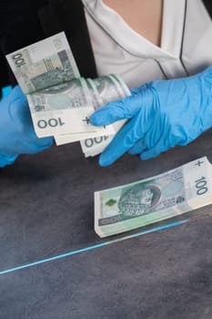 Hand counting banknotes by a young woman at the cashier's window in a large banking branch.