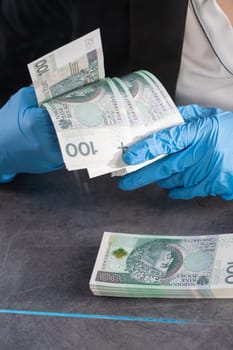 Hand counting banknotes by a young woman at the cashier's window in a large banking branch.
